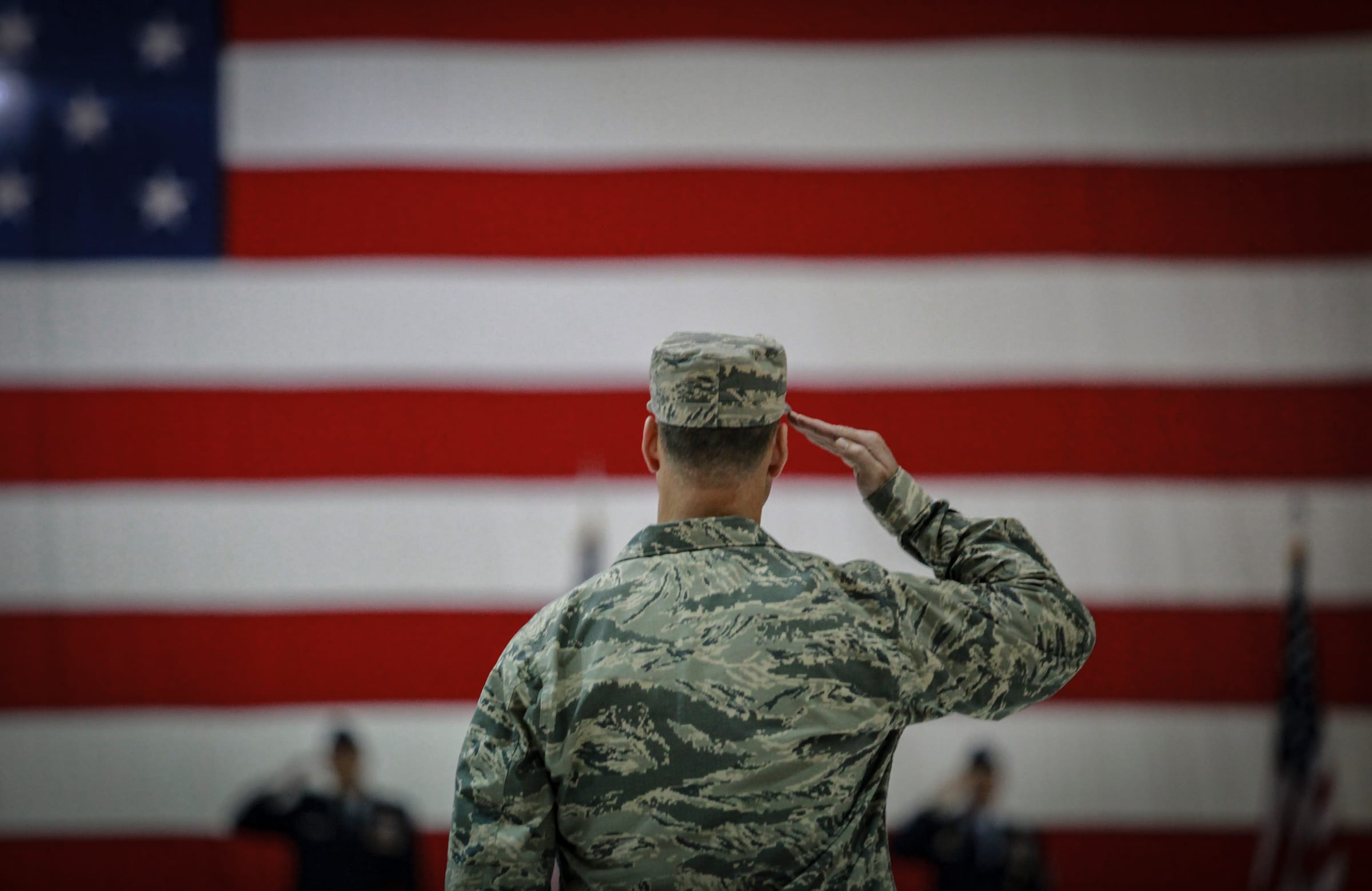 Airman saluting the American flag at a ceremony